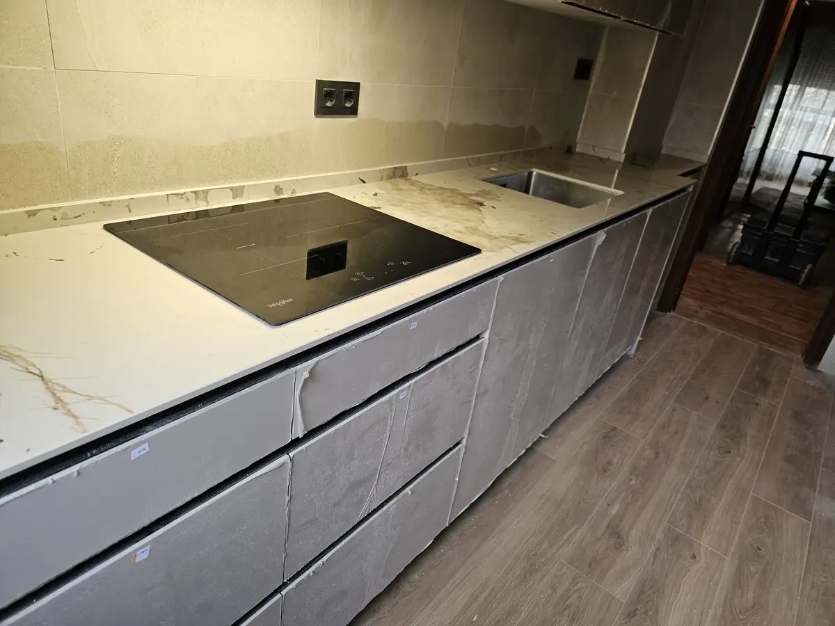 Cocina lineal gris mate con encimera blanca veteada y fregadero bajo encimera