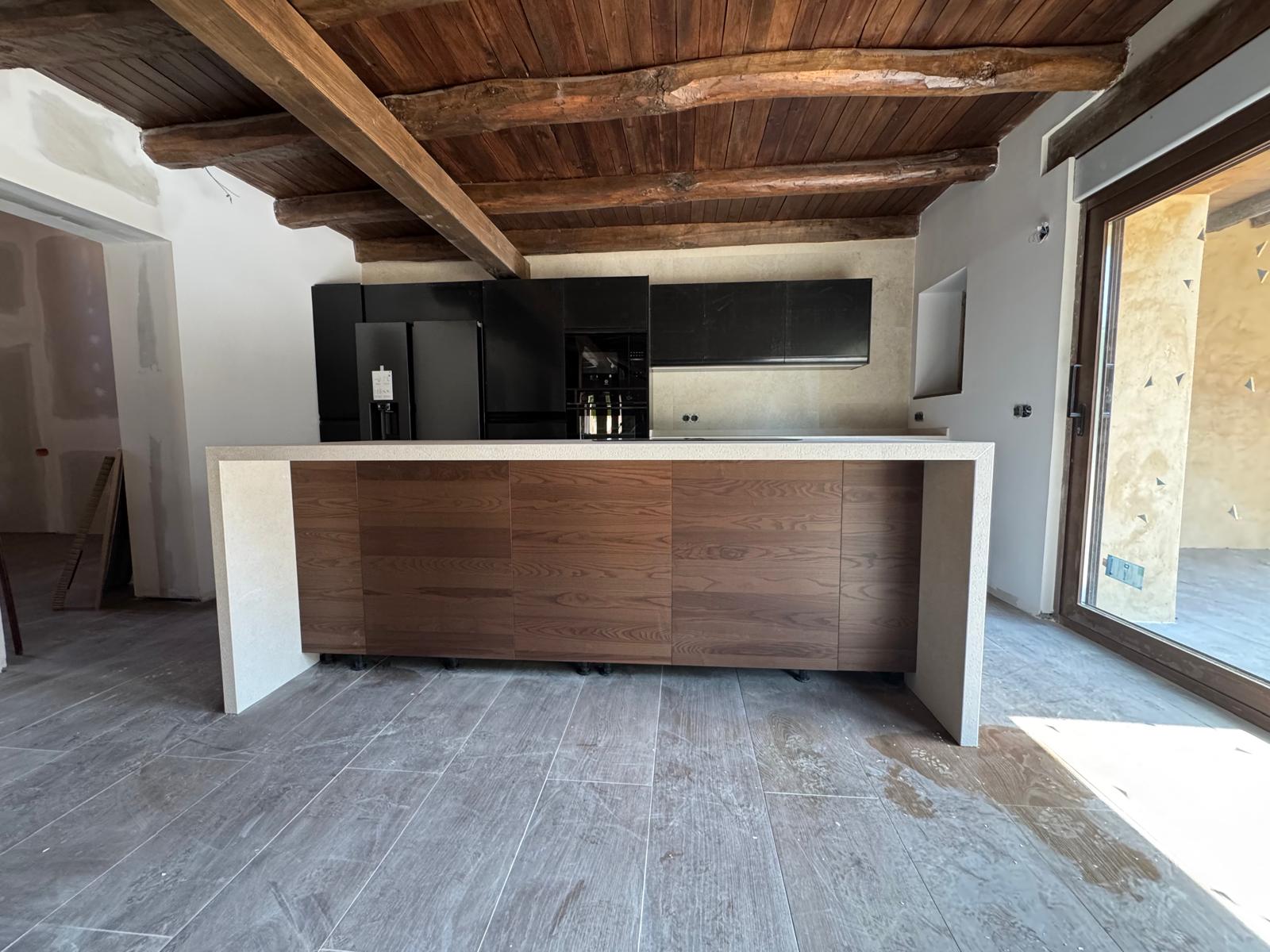 Cocina rústico-moderna con isla, nogal y muebles negros en León